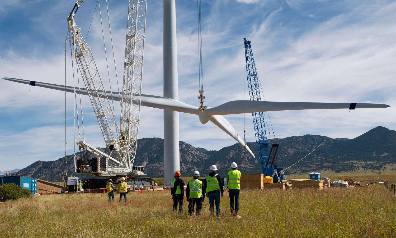 A wind turbine being assembled by a crew of workers.